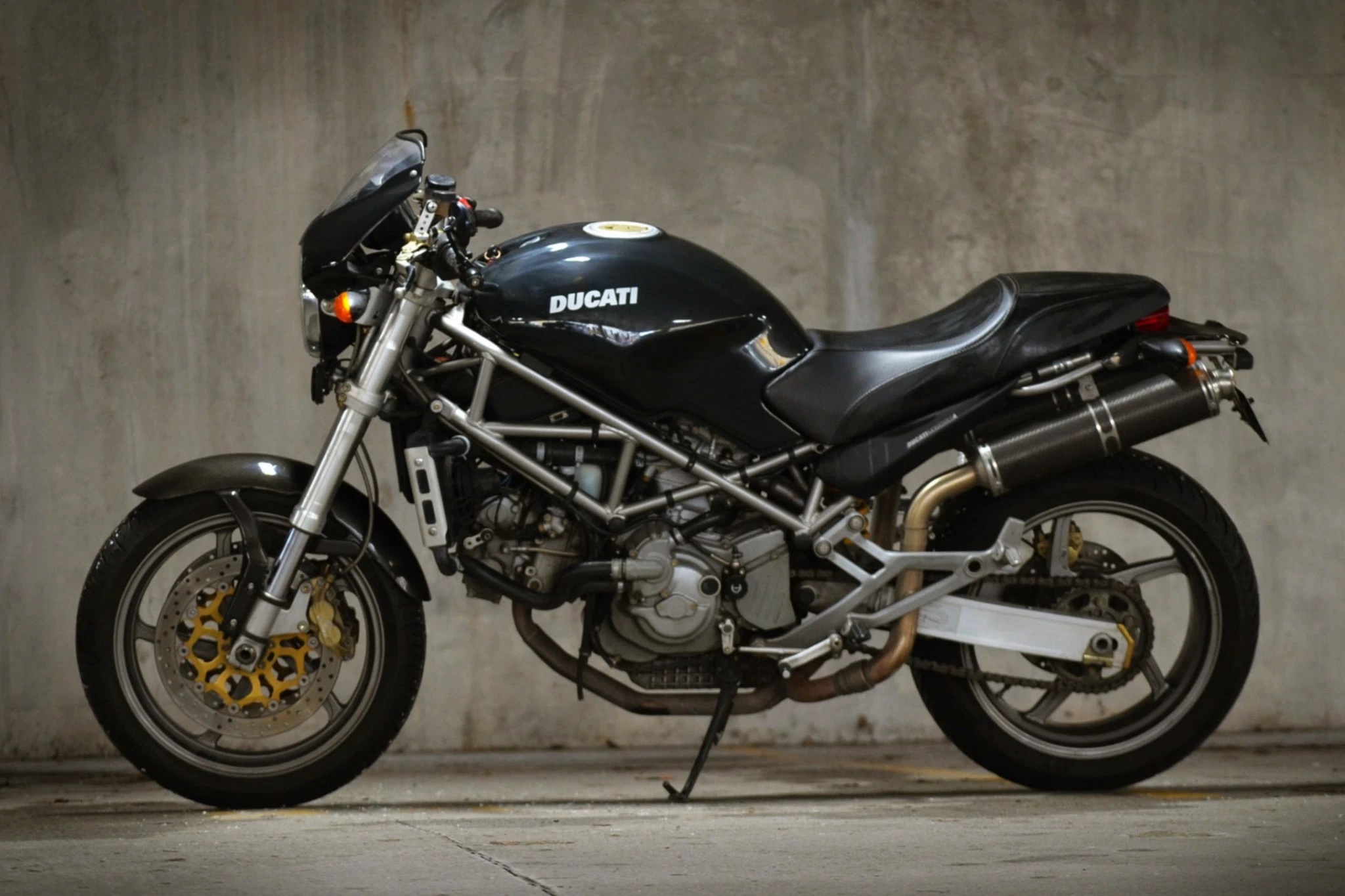 Black 2002 Ducati Monster S4, viewed from the side, in a concrete parking garage