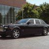 A blue Rolls-Royce Phantom sits in front of office building