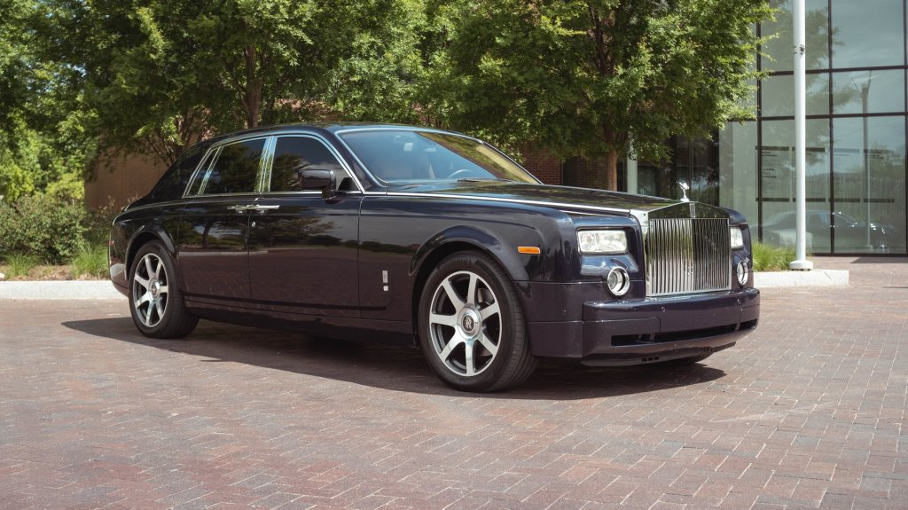A blue Rolls-Royce Phantom sits in front of office building