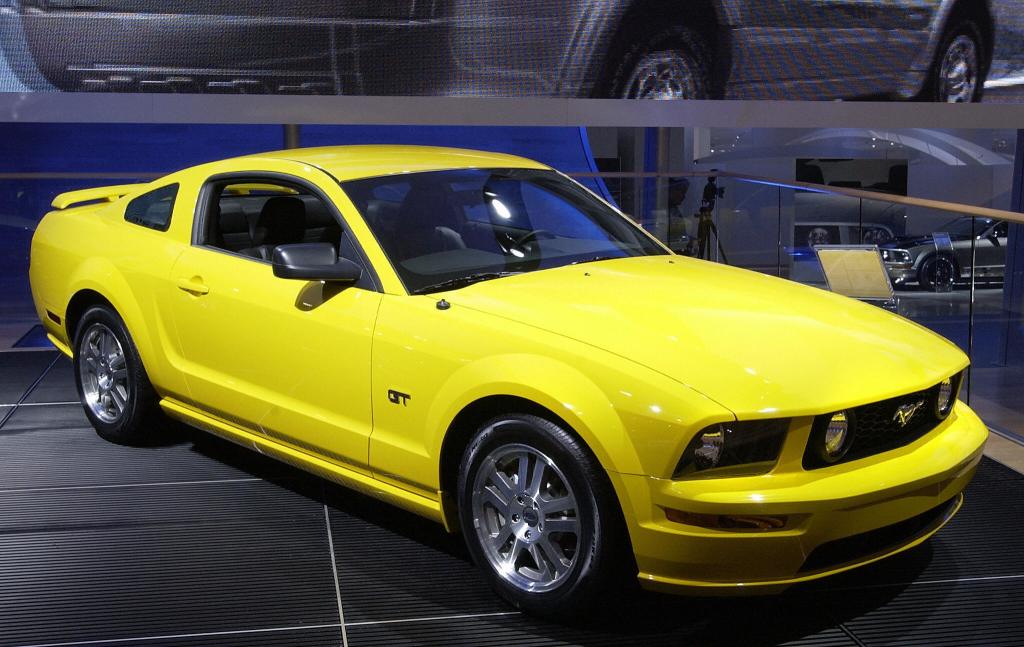 A yellow 2006 Ford Mustang on display at an auto show