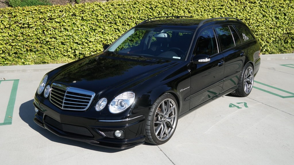 Black 2006 Mercedes E55 AMG Wagon in front of a green hedge