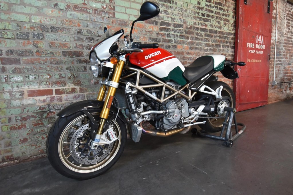 2008 Ducati Monster S4R S Tricolore motorcycle, with a tank painted in the Italian flag's colors, against a brick wall