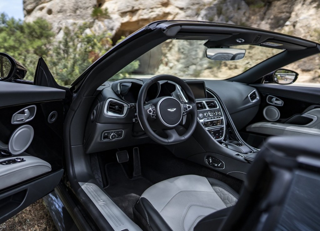 The 2020 Aston Martin DBS Superleggera Volante's front seats, dashboard, and center console, seen with the driver's door open