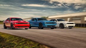 Three 2020 Dodge Challengers, red, white, and blue are on the track side by side.