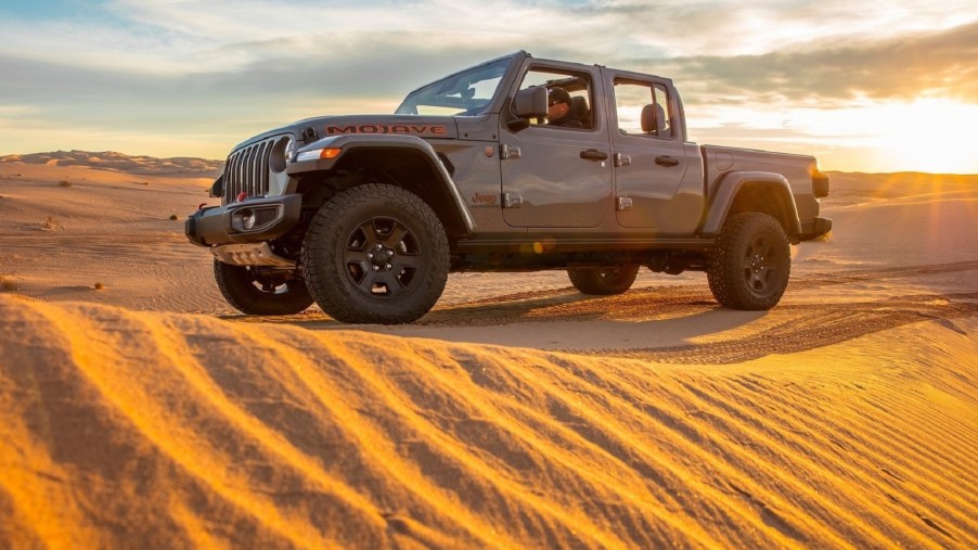 Grey-brown 2020 Jeep Gladiator Mojave truck crossing a dune at sunset