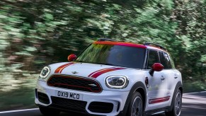 White-and-red-striped 2020 Mini Countryman John Cooper Works driving through a forest