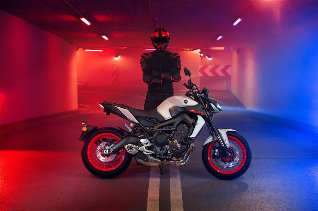 White 2020 Yamaha MT-09 standing in front of a blac-clad helmeted rider in a red-and-blue-lit tunnel