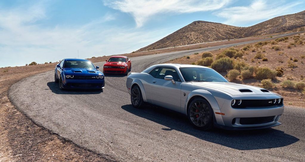 Three 2020 Dodge Challengers are on the track at the same turn together.