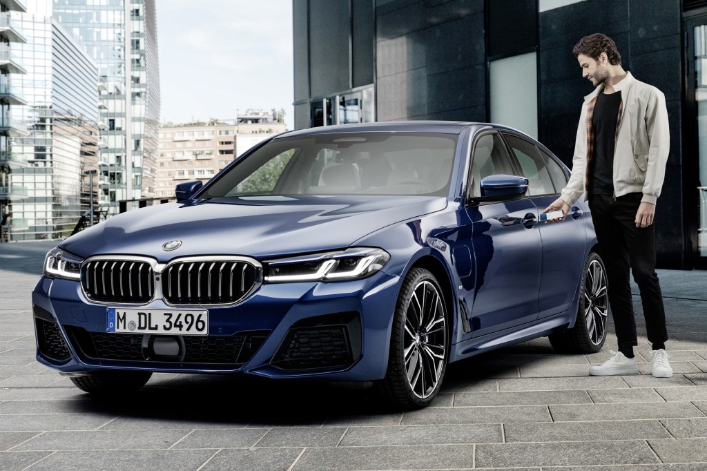 Unlocking a dark-blue 2021 BMW 5-Series sedan with an iPhone using Apple CarKey