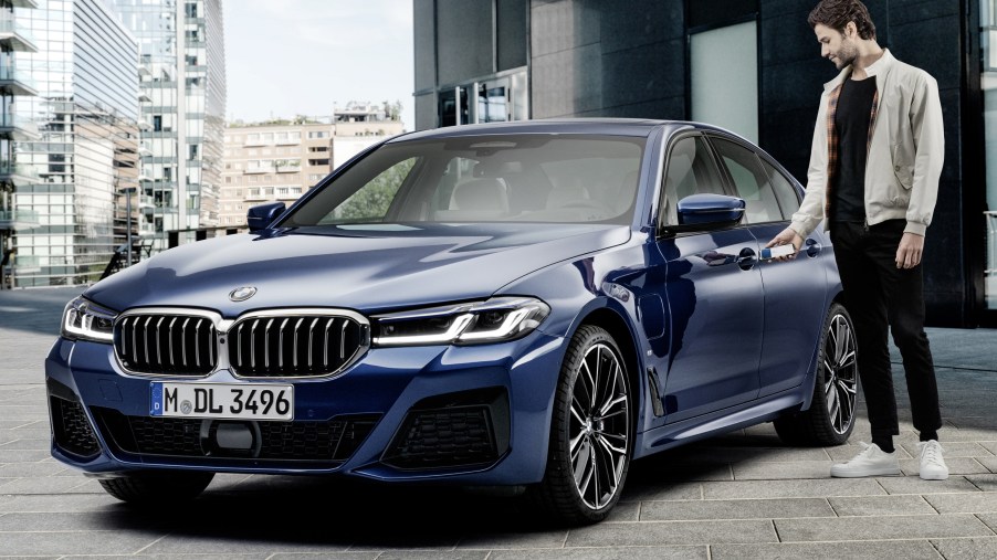 Unlocking a dark-blue 2021 BMW 5-Series sedan with an iPhone using Apple CarKey