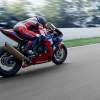 a red, white, and blue CBR1000RR-R sport bike racing down the street