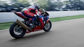 a red, white, and blue CBR1000RR-R sport bike racing down the street