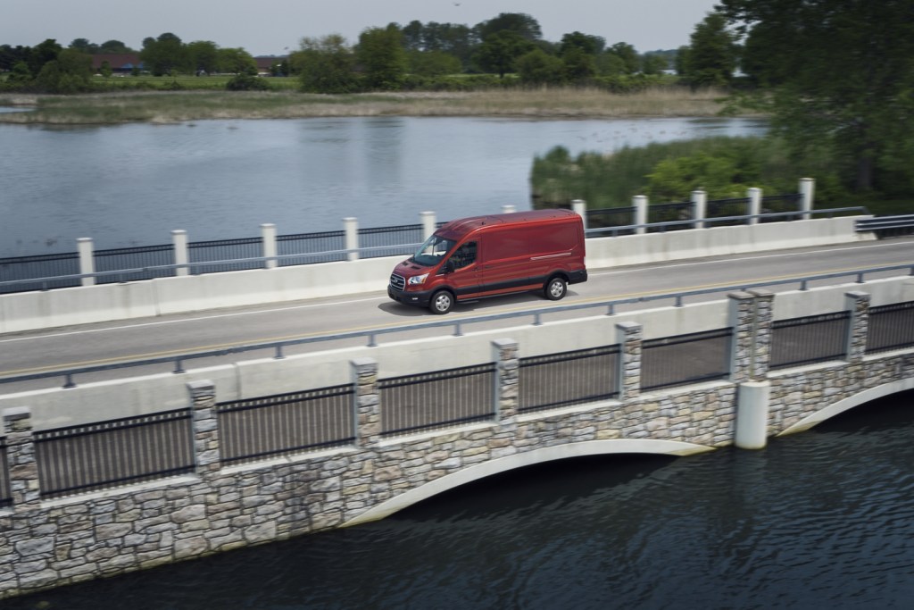 A red 2020 Ford Transit Cargo driving over a bridge