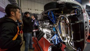 Visitors look at the aftermarket exhaust of a sideways-turned car