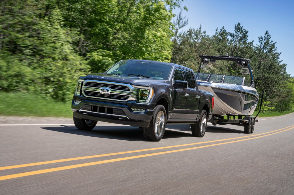 A gray 2021 Ford F-150 Hybrid towing a boat