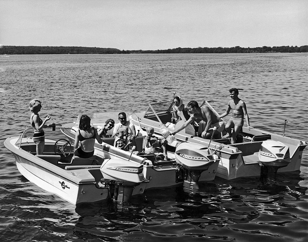 Three sets of boaters with Evinrude motors gather together on the lake to share food and drink, late 1950s or early 1960s. (Photo by Underwood Archives/Getty Images)