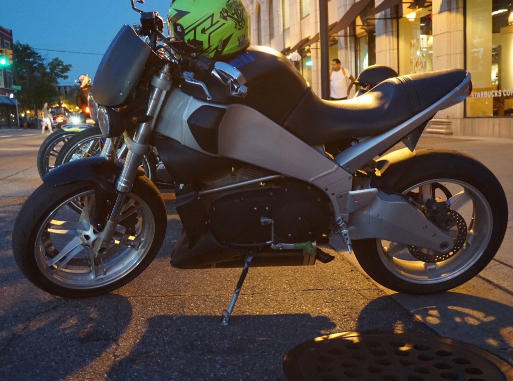 Black-and-silver Buell Lightning with green helmet on a city street