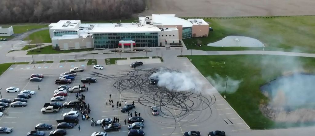 Tire burnouts and donuts are clearly visible in the markings of a church parking lot