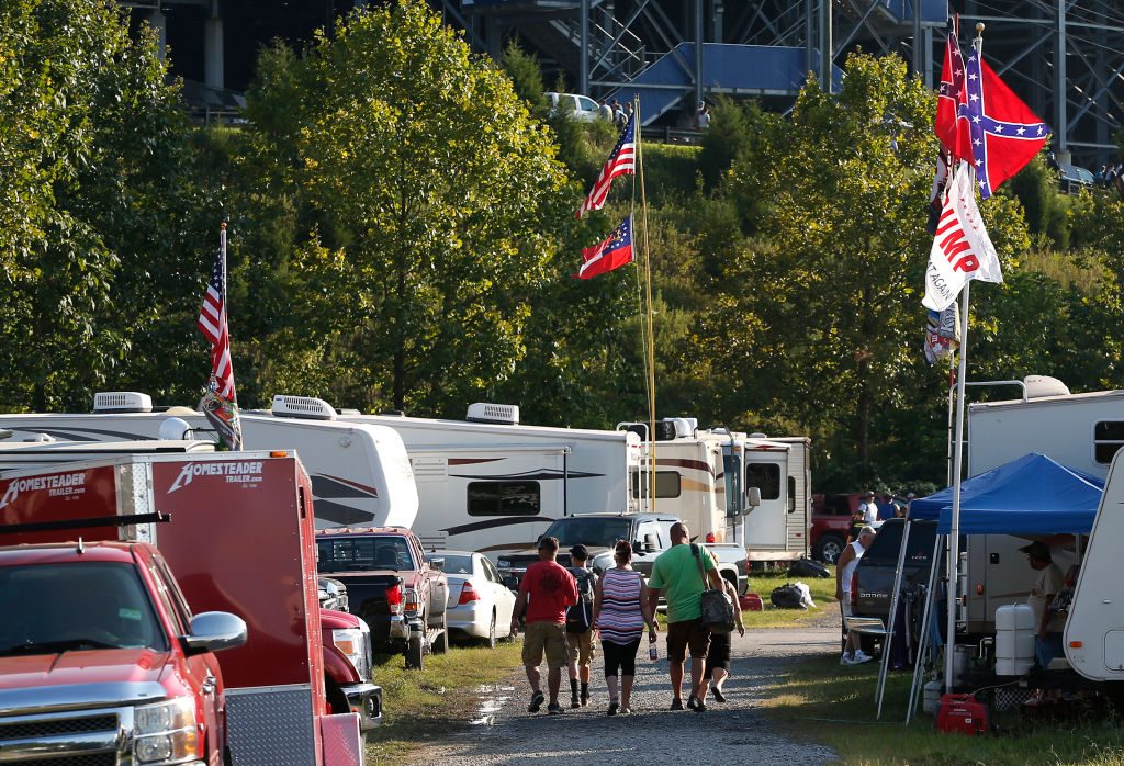 NASCAR fans walk past a pair of Confederate flags and a Trump flag as they make their way to the Bass Pro Shops NRA Night Race in Bristol, TN 