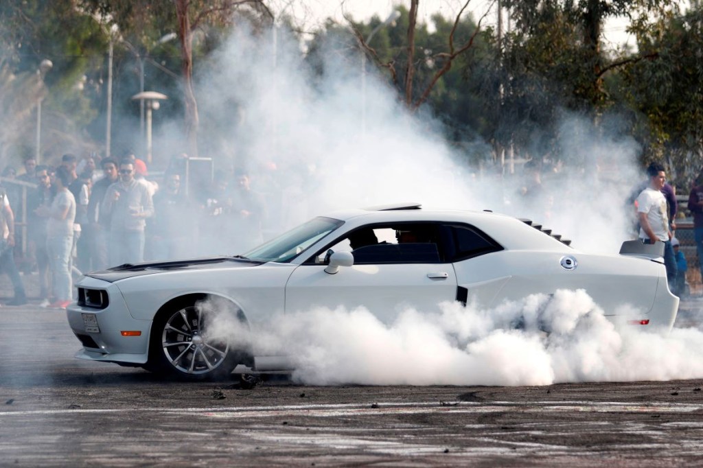 The driver of a white Dodge Challenger performs a burnout 