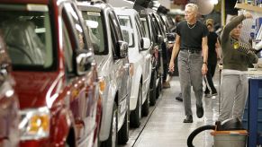 A man inspecting a row of minivans in a factory