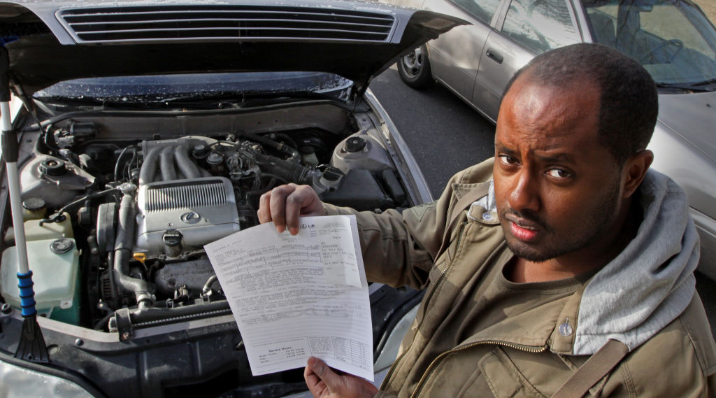 An oil change technician holds up a bill for the work.
