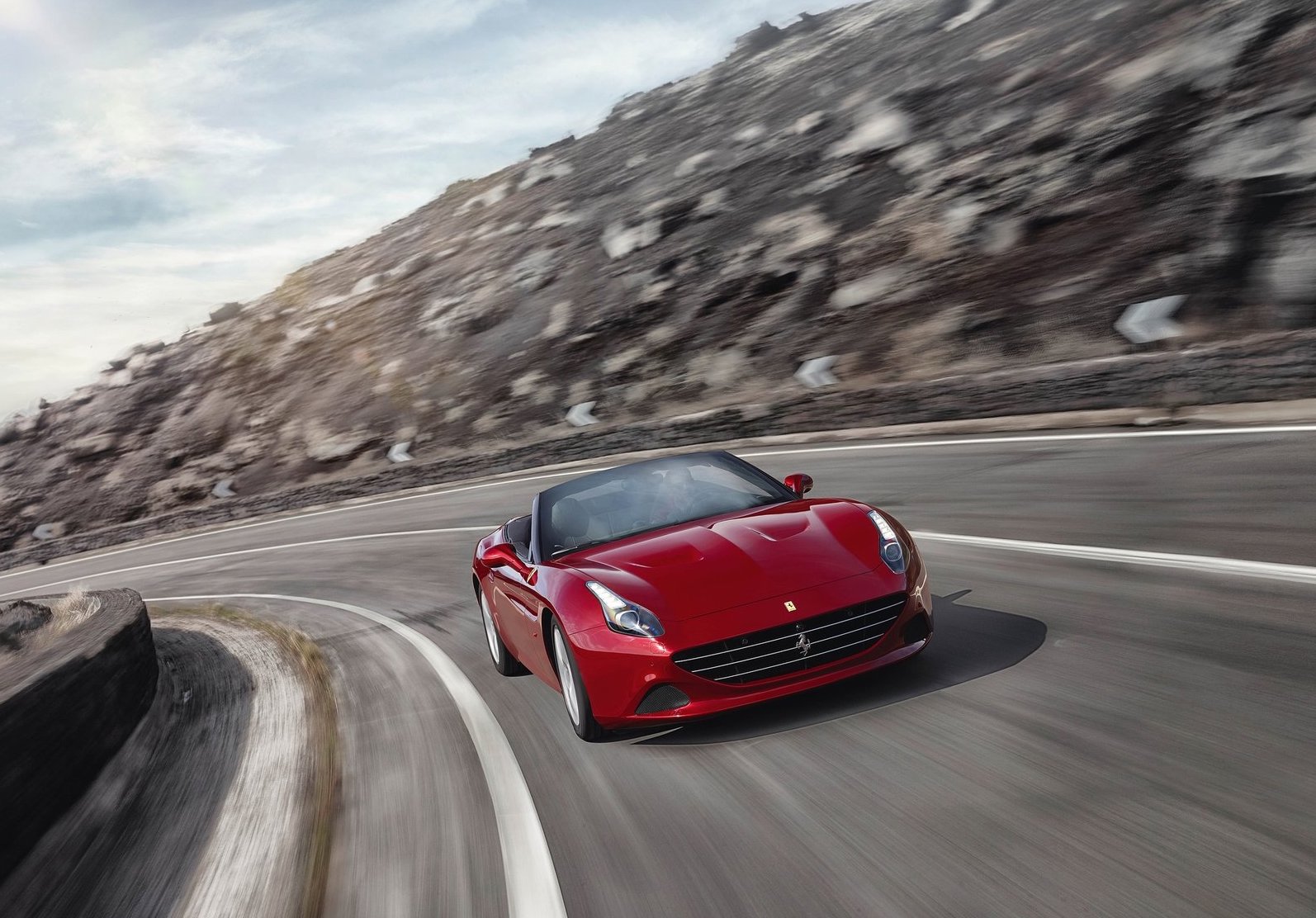 a red Ferrari driving fast on a winding mountain road