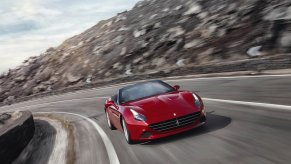 a red Ferrari driving fast on a winding mountain road