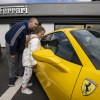 A father and his daughter looking at a new yellow Ferrari