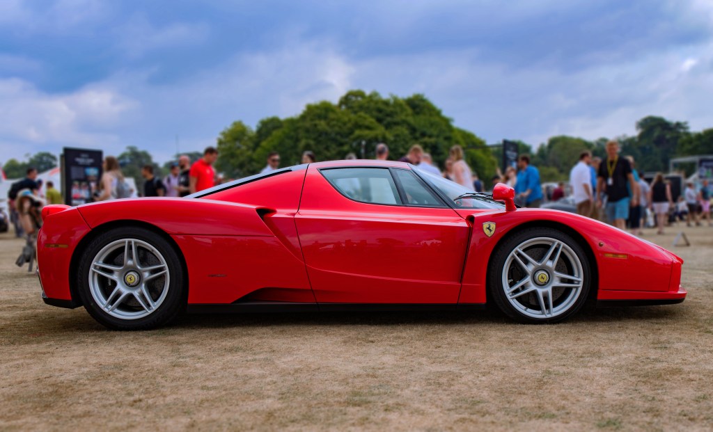 A rare Ferrari Enzo in red on a lawn at a car show representing the car company 