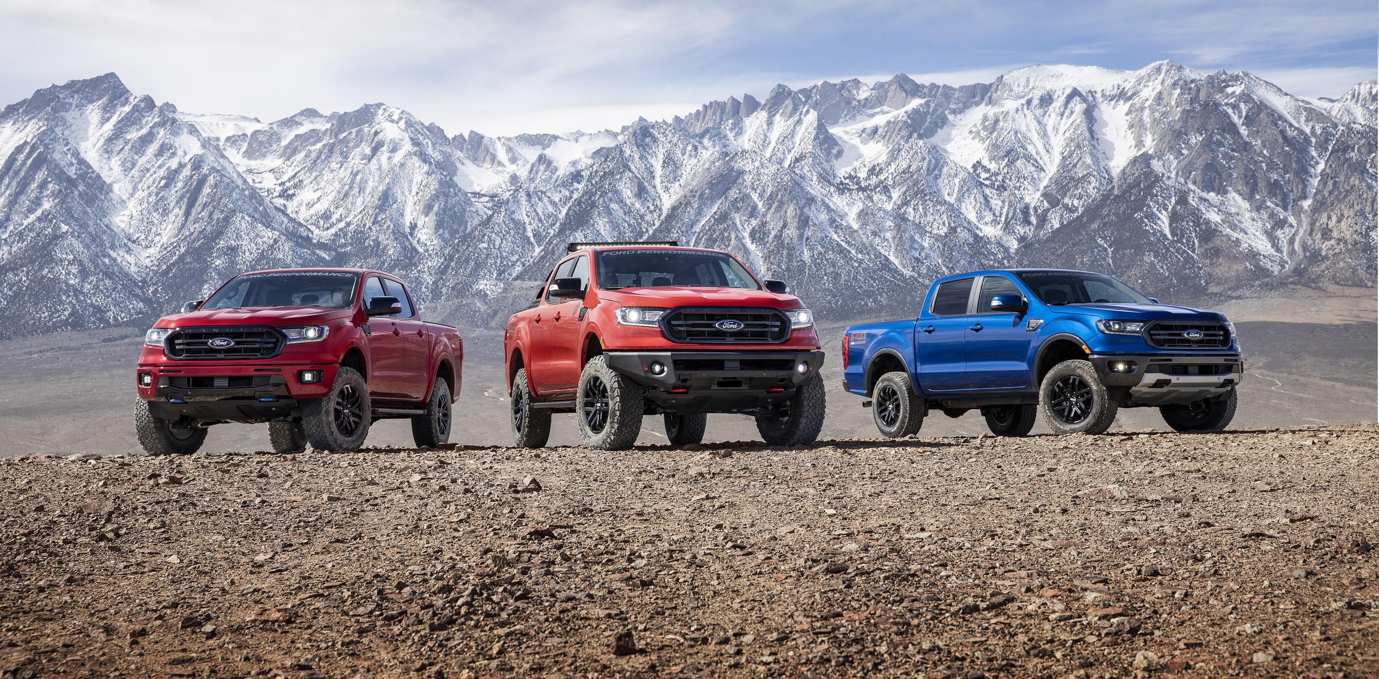 Red Level 2, orange Level 3, and blue Level 1 Ford Performance-modified Rangers in front of a mountain range
