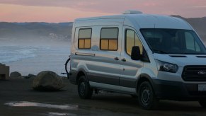 A Ford Transit van that has been converted for van life sits by the beach ready for everyone and the dog