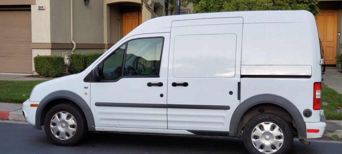 A Ford Transit work van parked outside a house.
