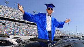 A high school senior in cap and gown arrives at his graduation at Daytona International Speedway