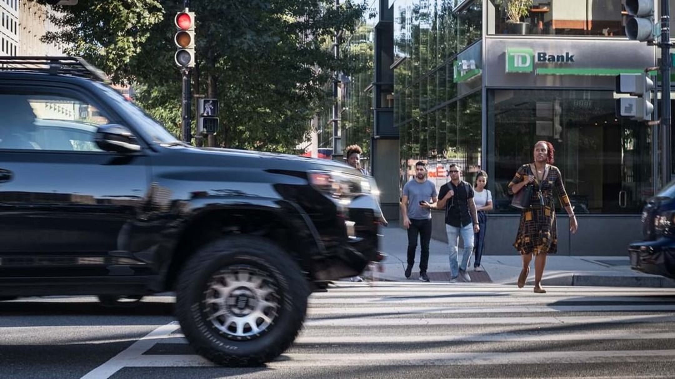 An SUV drives close over a pedestrian crossing in a city