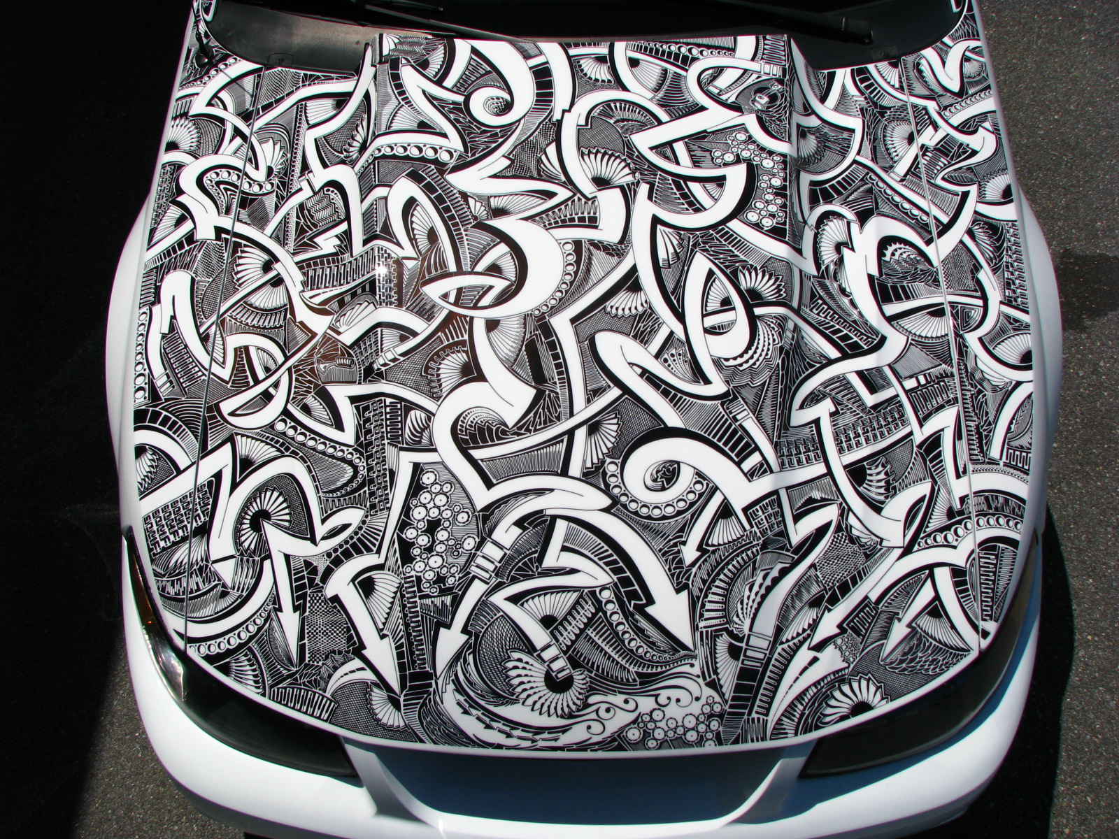 A white Mustang's hood is covered in marker art