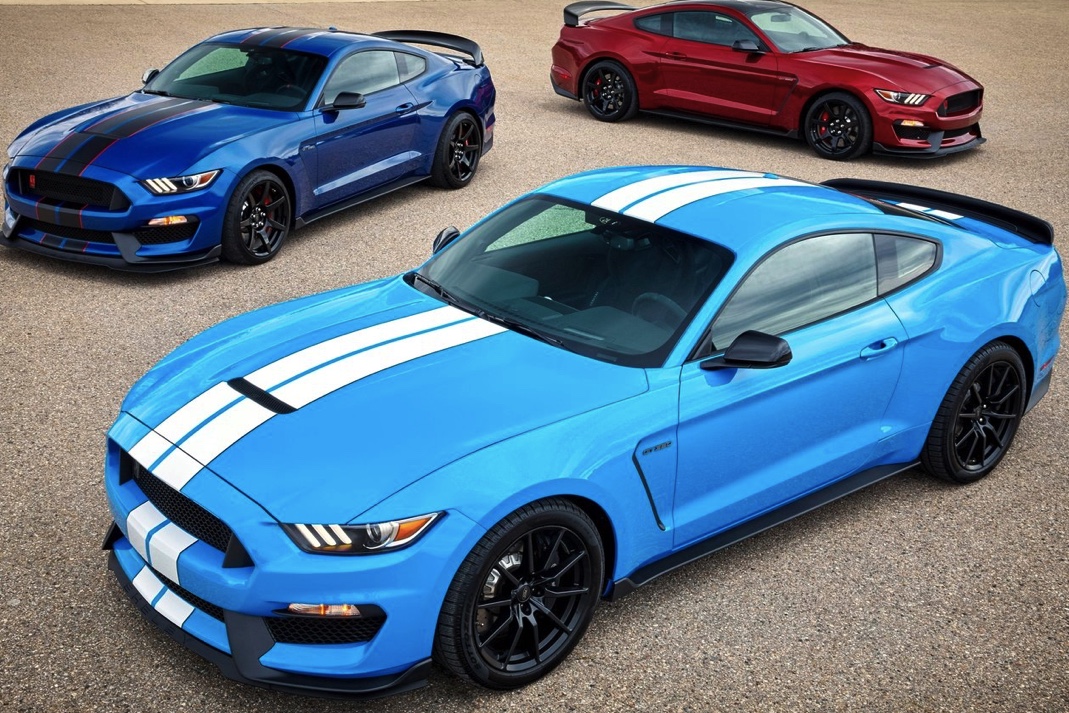 three Mustang GT350s. A red one and dark blue with a candy blue 2017 Ford Mustang in the foreground