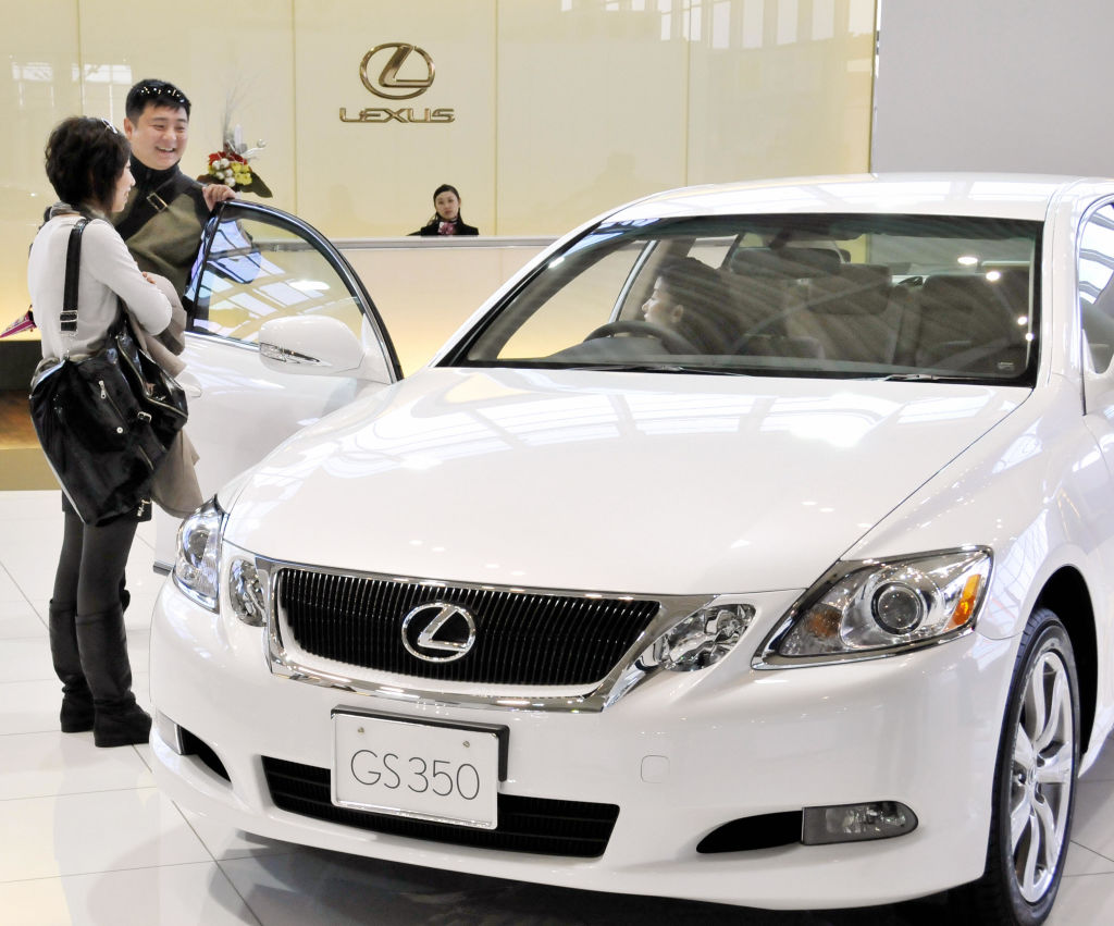Customers inspects a Lexus car on a showroom floor