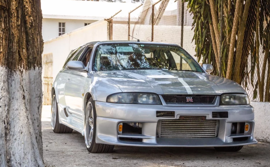 front 3/4 Nissan Skyline converted into a wagon in front of wall