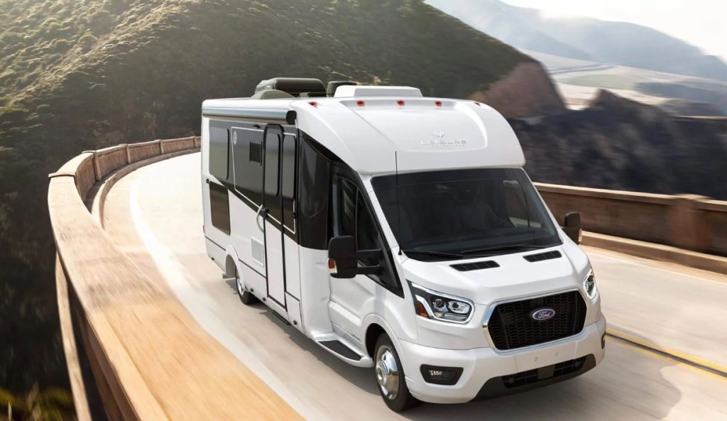 A large new RV motor home driving up a winding mountain pass