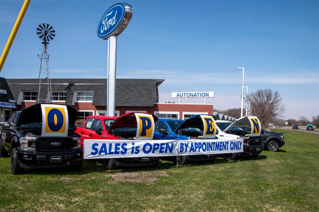 A banner in front of a dealership says, sales by appointment only.