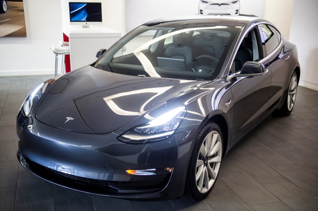 A charcoal Tesla Model 3 electric car in a showroom