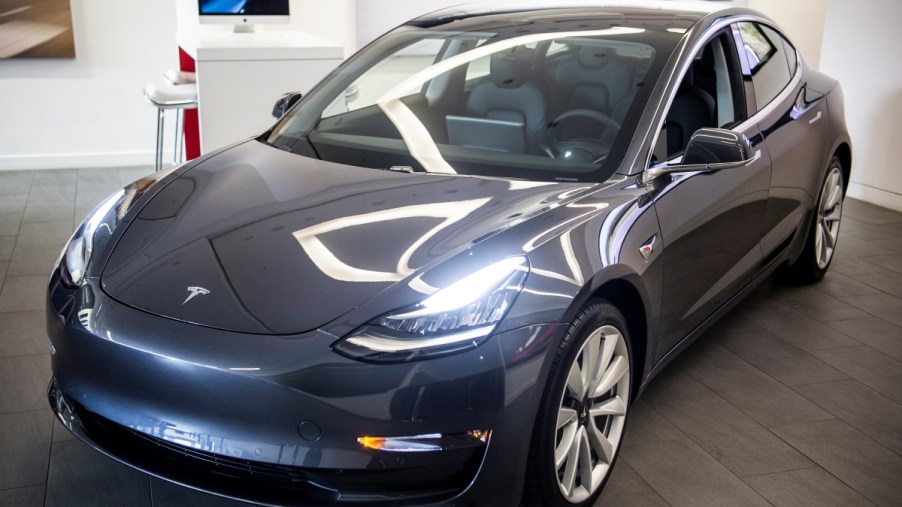A charcoal Tesla Model 3 electric car in a showroom