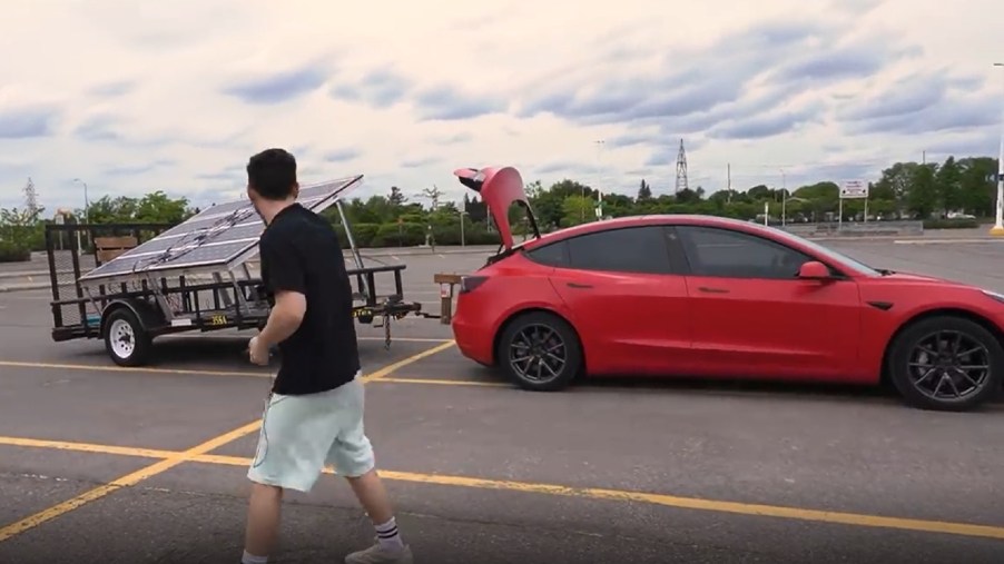 Red Tesla Model 3 with homemade solar panel trailer