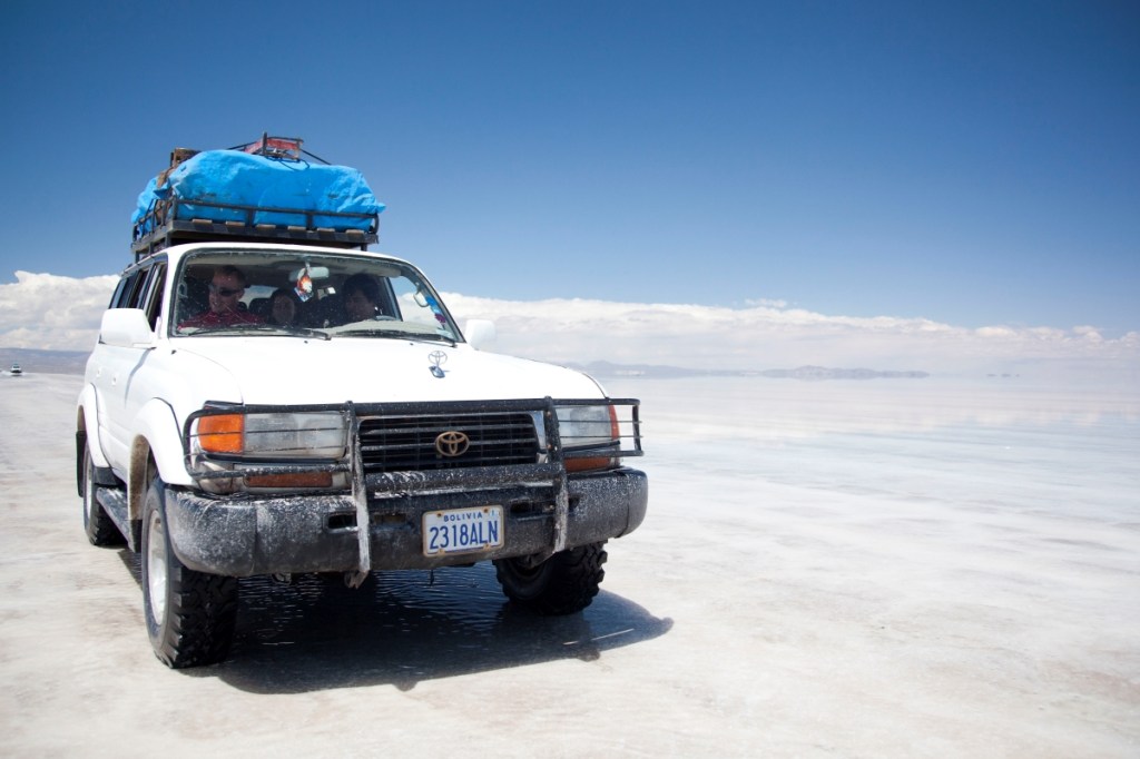 A white Toyota Landcruiser crosses Salt Flats in Bolivia