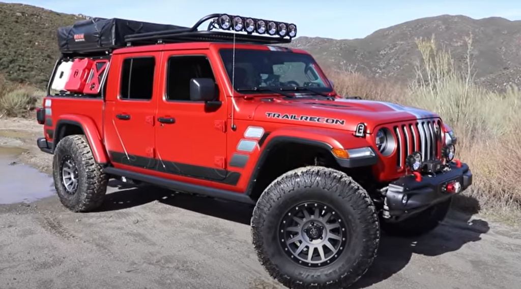 A red Jeep Gladiator parked on a dirt road