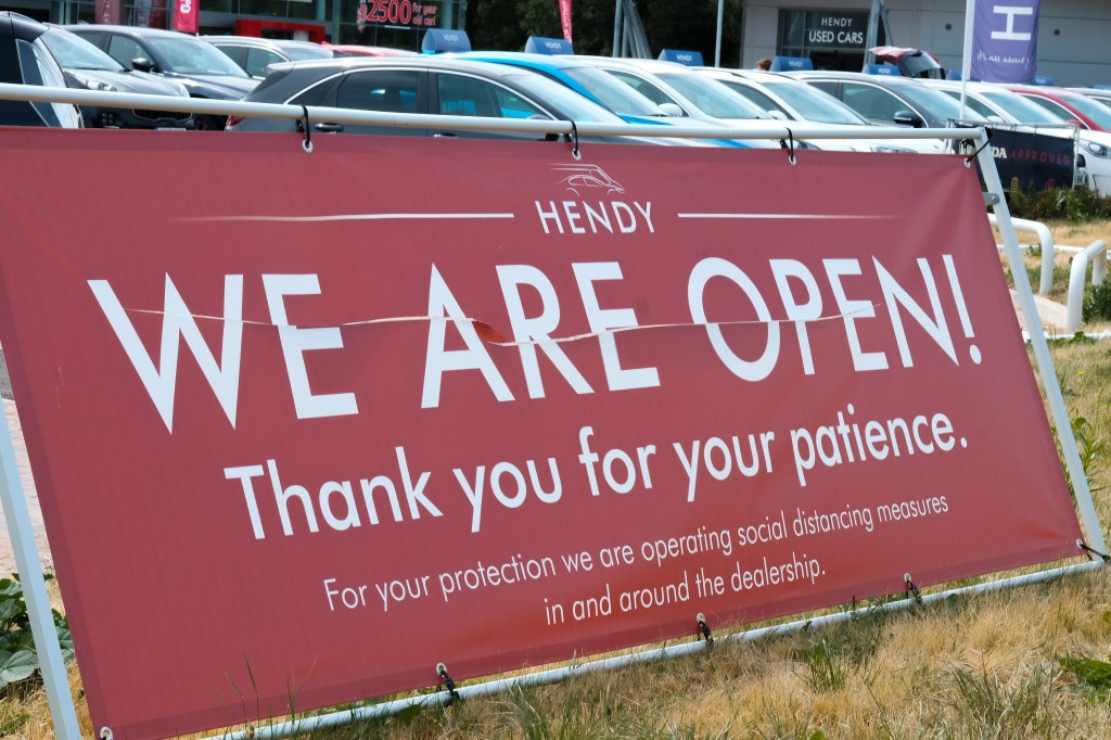 A, We Are Open, sign is in front of a car dealership. Re-opened after taking COVID-19 precautions.