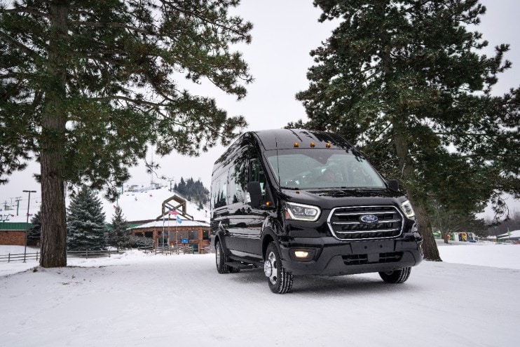 A black Ford transit passenger van in the snow