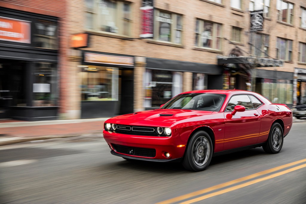 A red Dodge challenger driving on a city street