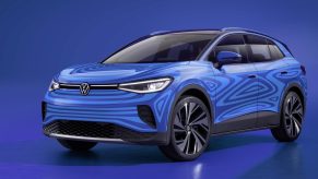 A blue Volkwagen electric SUV sits on display before a blue background.